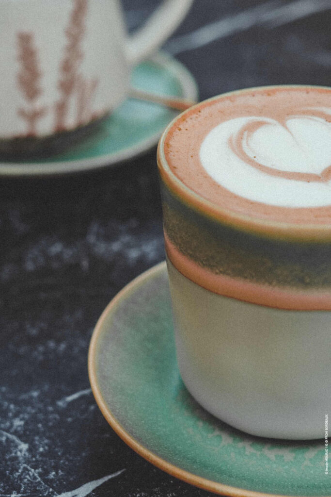 A cup and saucer containing a hazelnut latte with a latte art heart on top