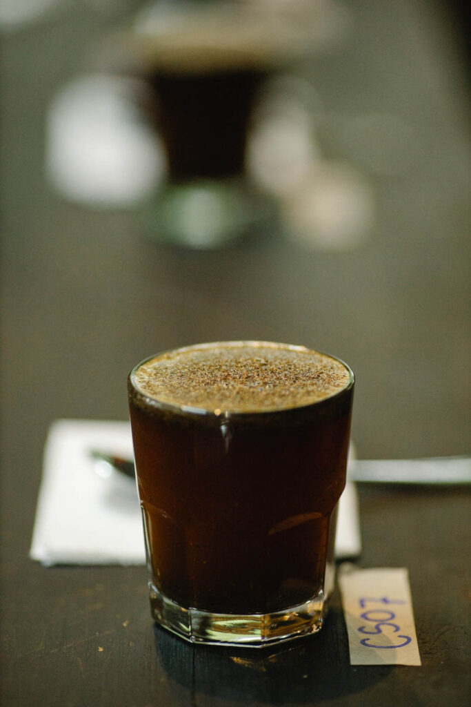 Fresh ground coffee brewing in a glass standing on a wooden table