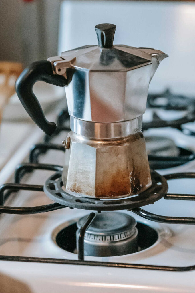 A moka pot on a stove brewing coffee
