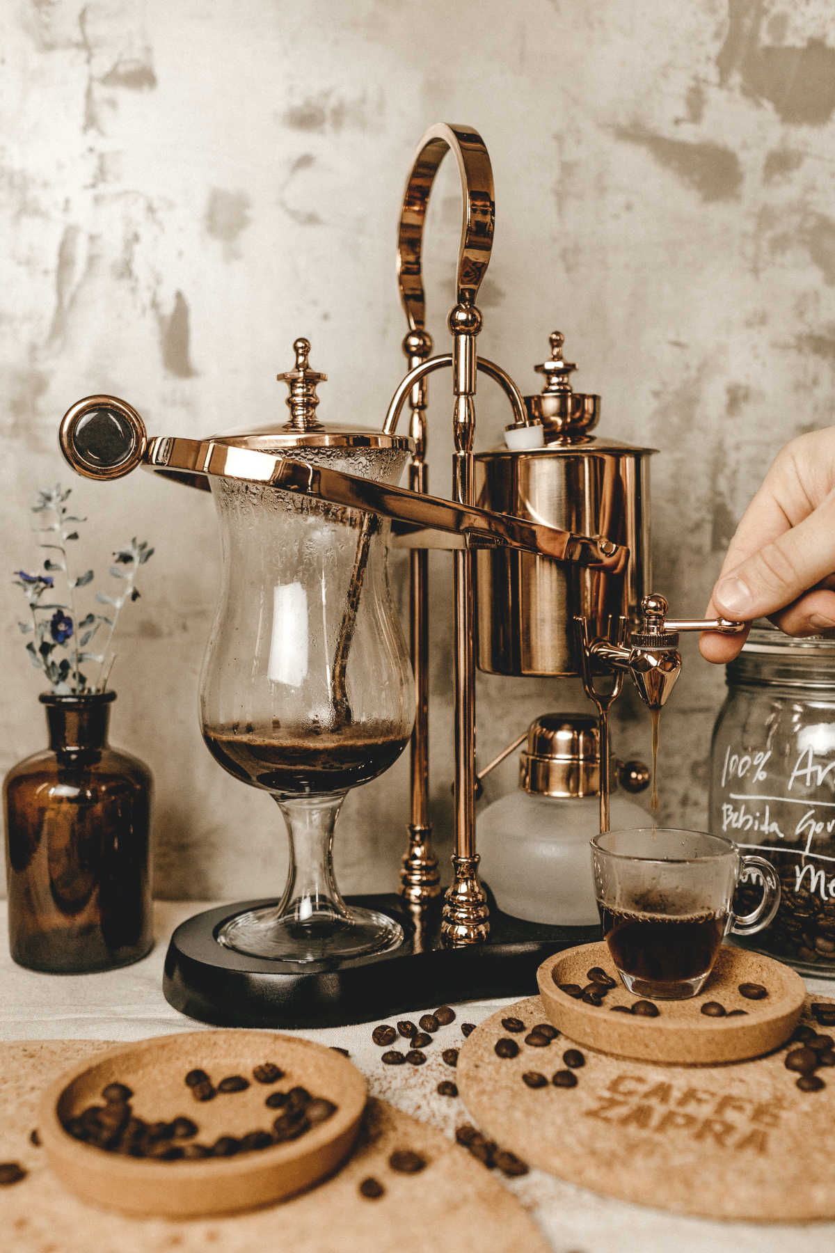 Brewing coffee with an old fashioned coffee maker, with bowls of coffee beans in the foreground.