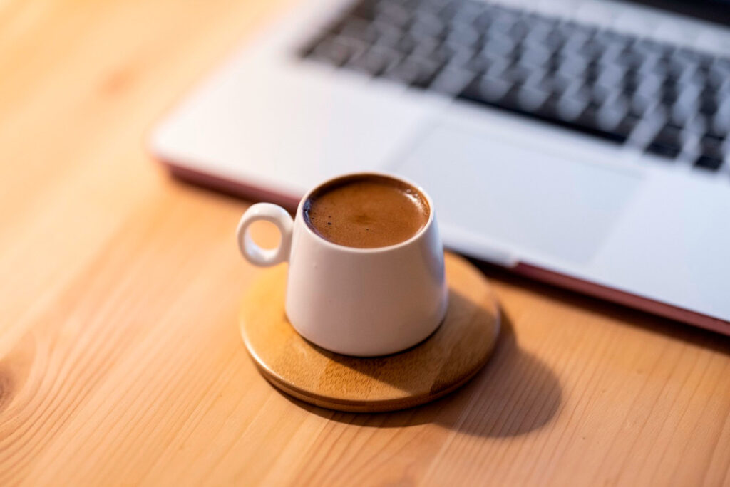 Cup of very strong coffee in a small cup standing on a wood coaster