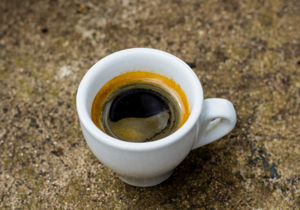 A cup of espresso sitting on a rough surface.