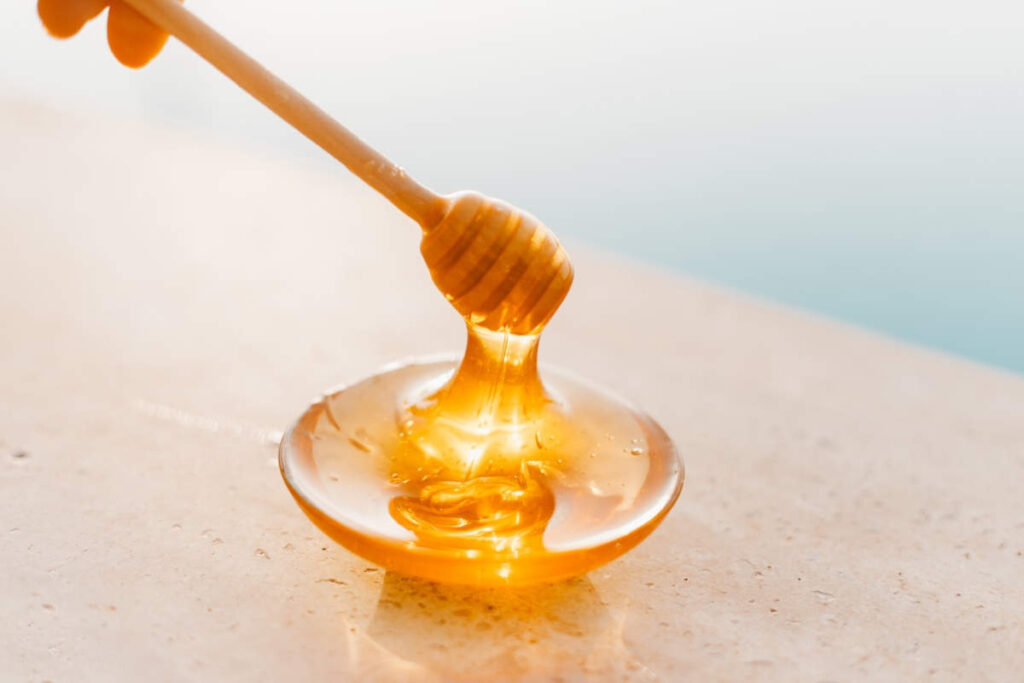 Honey drizzling from a wooden honey spoon.