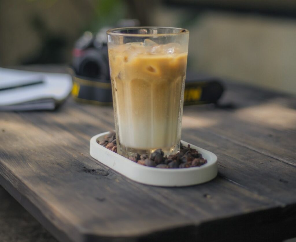 A large glass of iced gingerbread latte standing on a wooden table