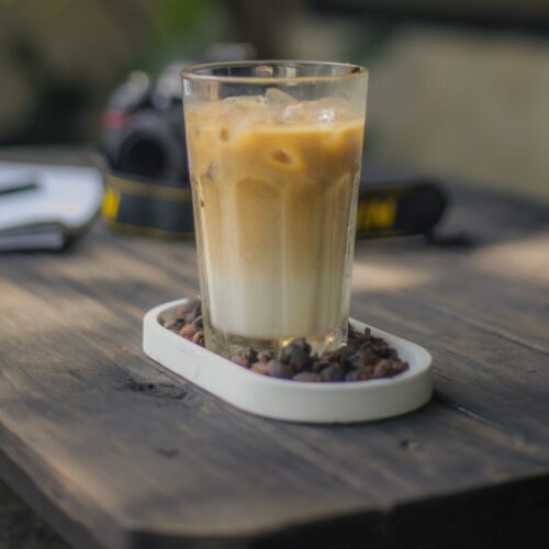 A large glass of iced gingerbread latte standing on a wooden table